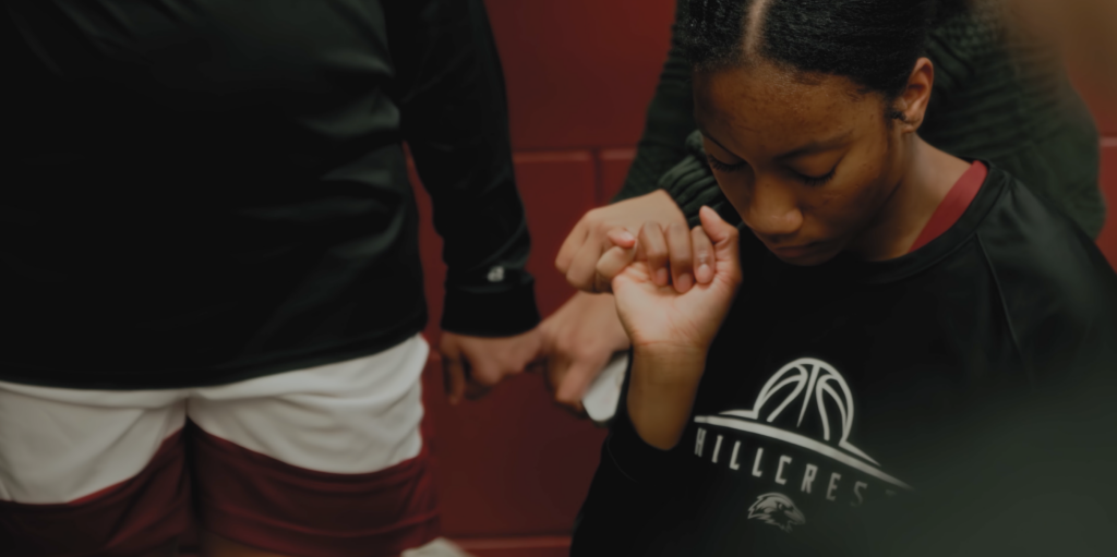 Hillcrest Academy basketball team huddling before a game, captured through dynamic sports storytelling